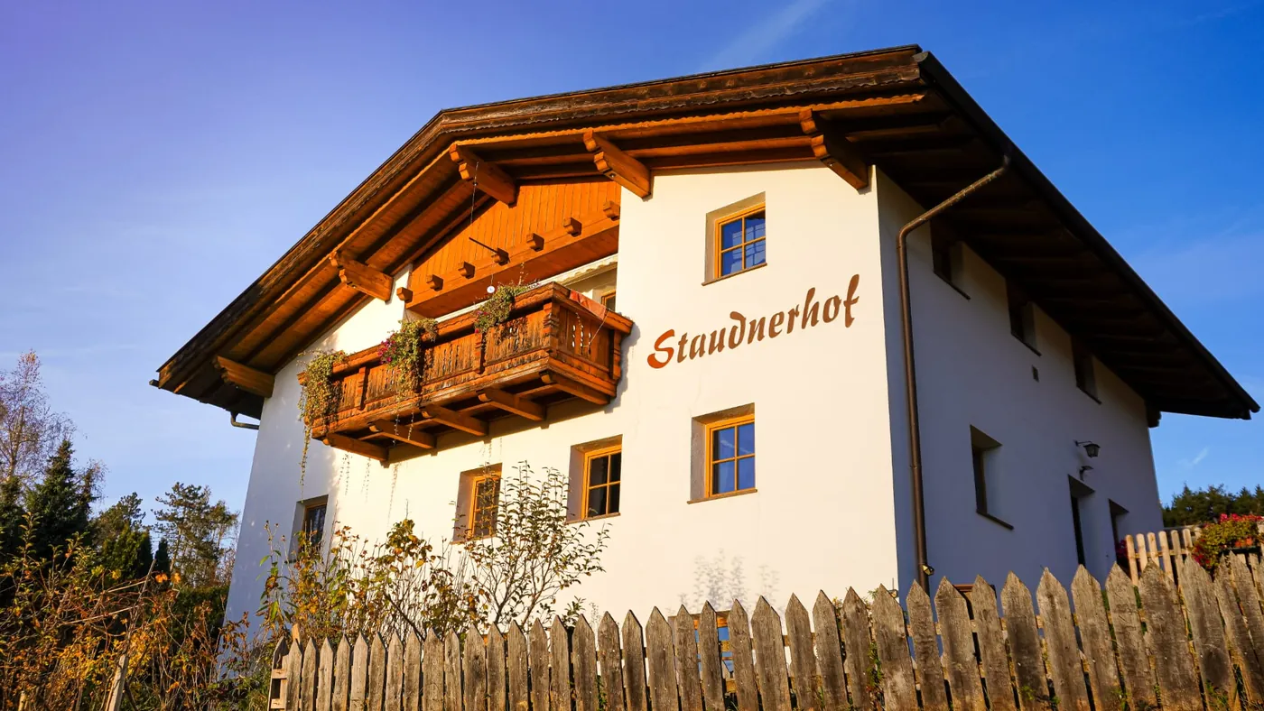 Der Staudnerhof im Sommer, Balkon mit Blumen und der Schriftzug an der Fassade